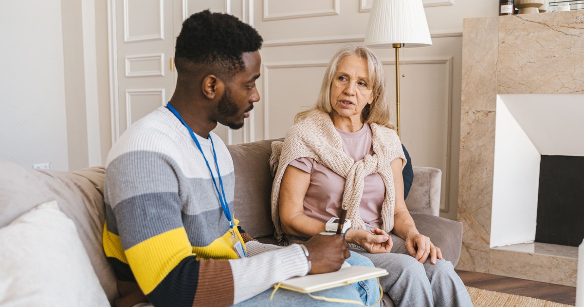 Care coordinator with a notebook talking with a senior client at home
