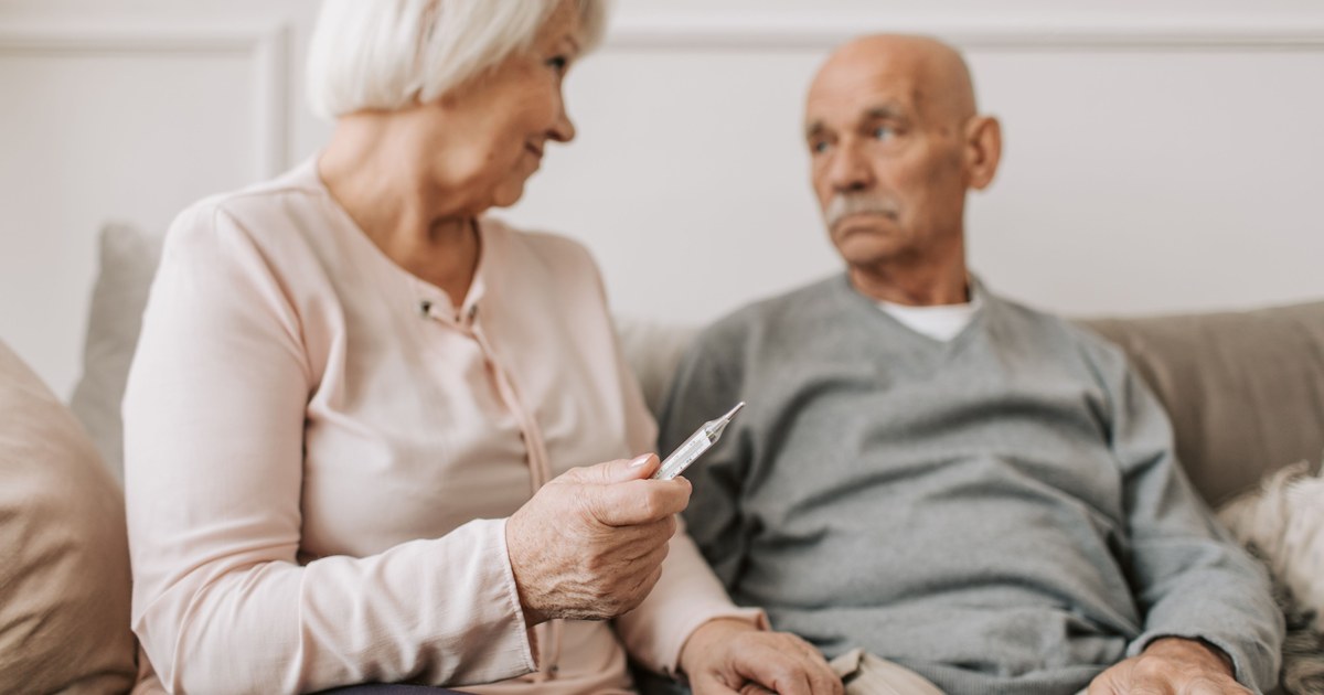 Spouse checking temperature of an elderly partner at home