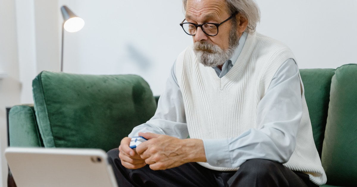 Senior man checking a pulse oximeter at home on the couch