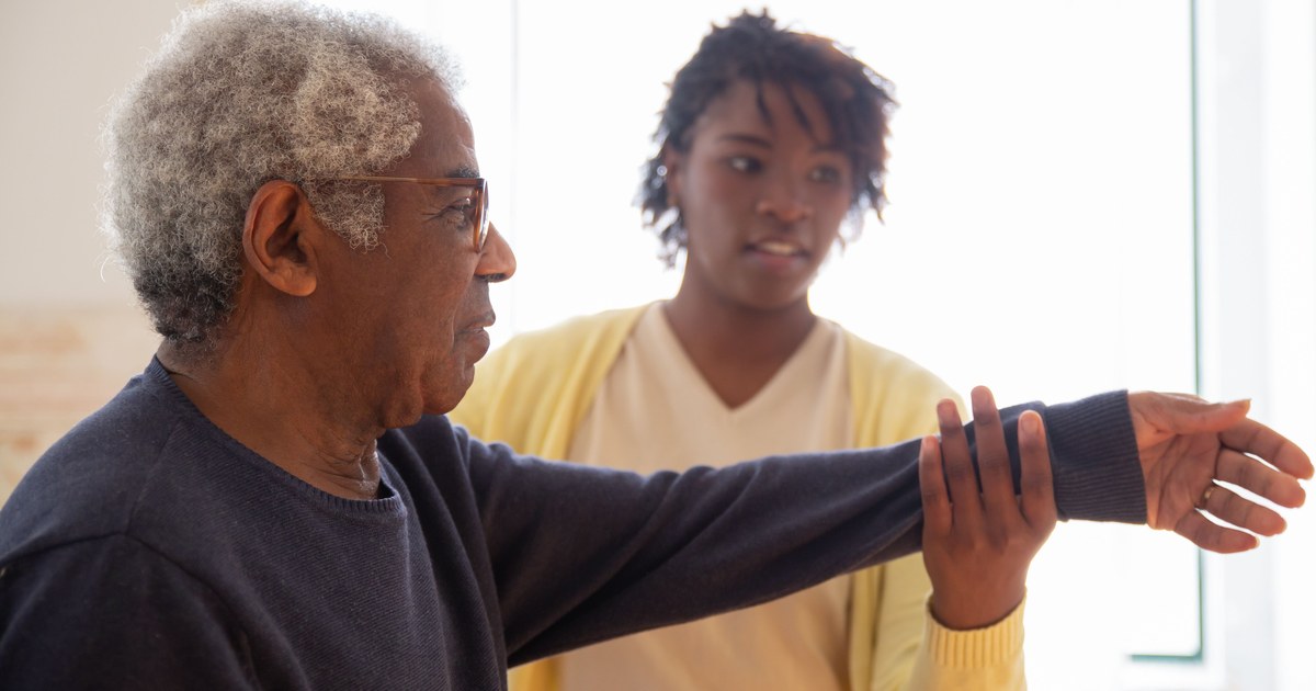 Caregiver helping a senior man with arm rehabilitation exercises