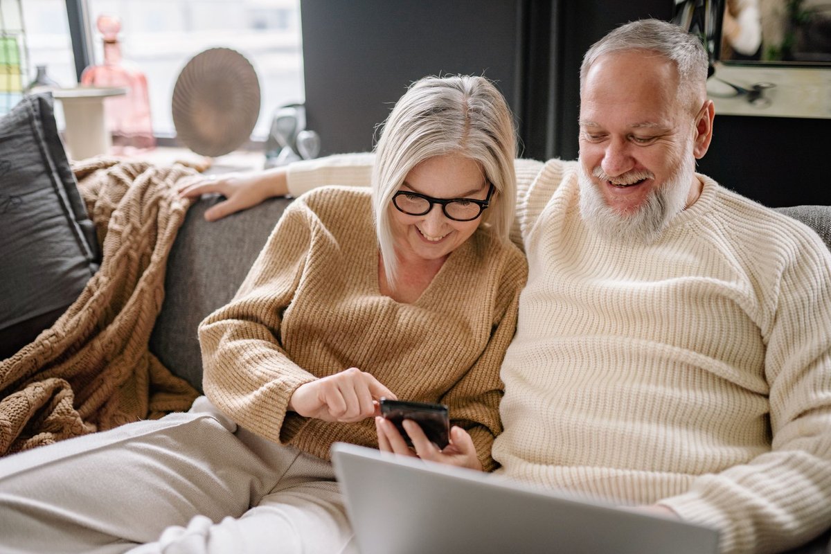 Older couple on a sofa looking at a smartphone together to check an app