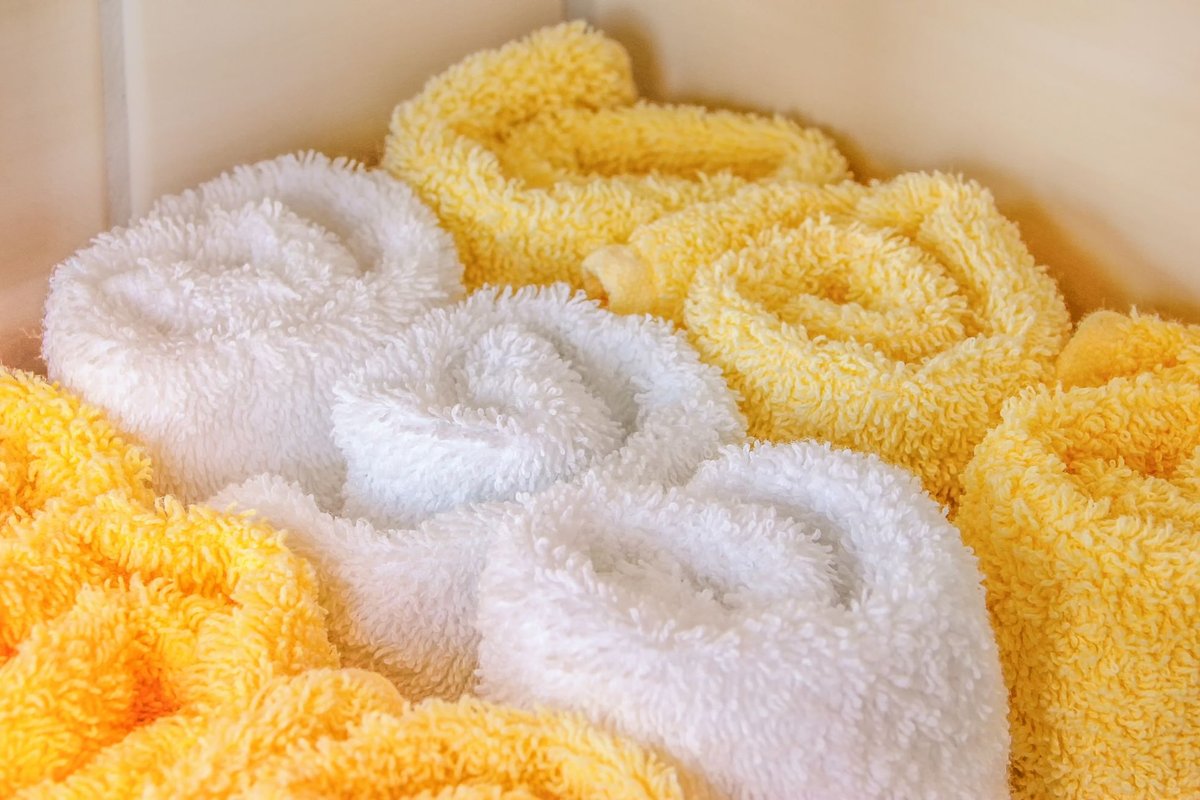 Rolled white and yellow bath towels stacked neatly and ready to use