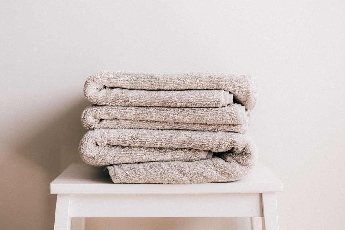 Stack of clean folded towels on a white stool, ready for daily care