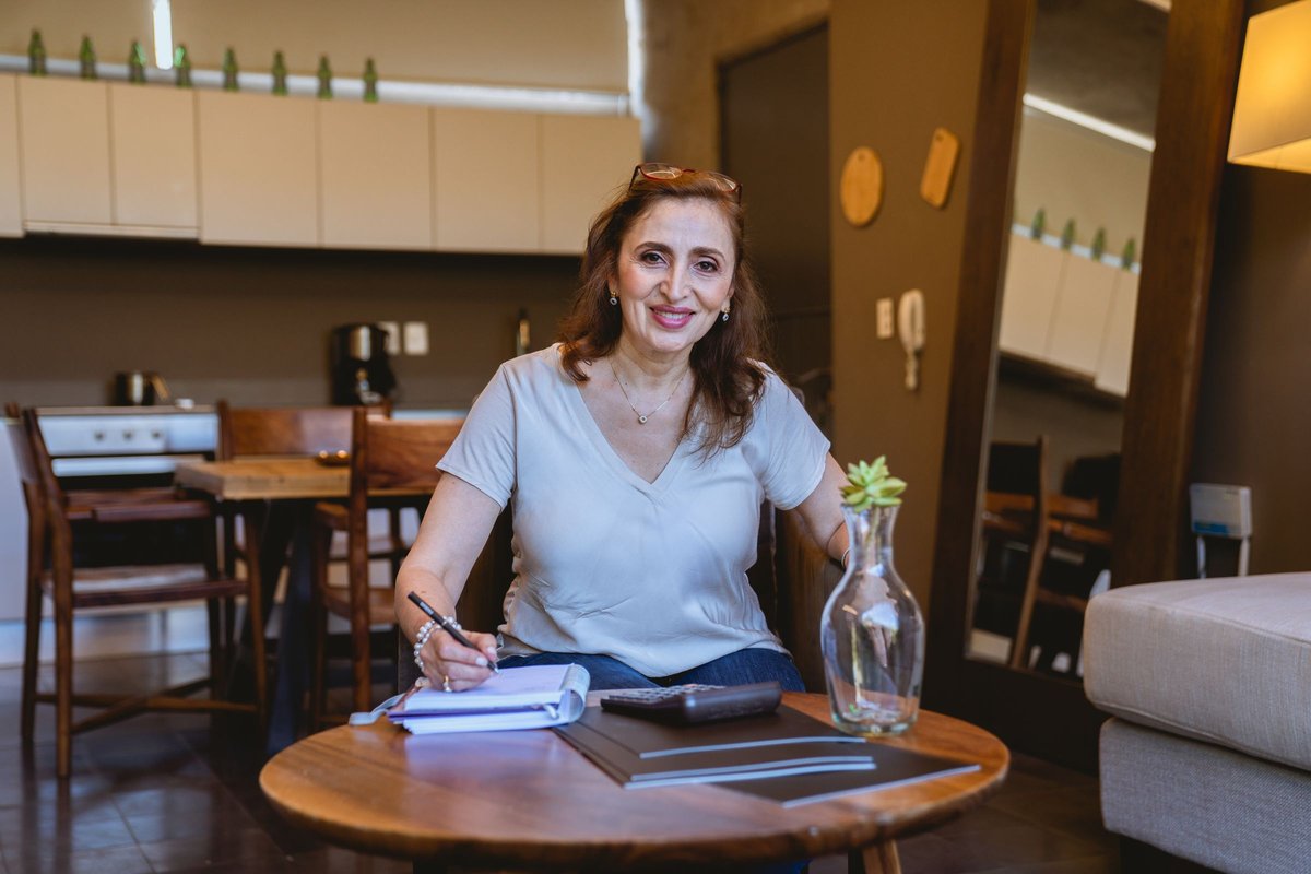 Smiling woman writing in a notebook at a kitchen table