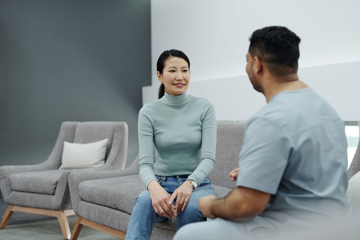 Smiling woman in a gray sweater talking with a health care worker in scrubs