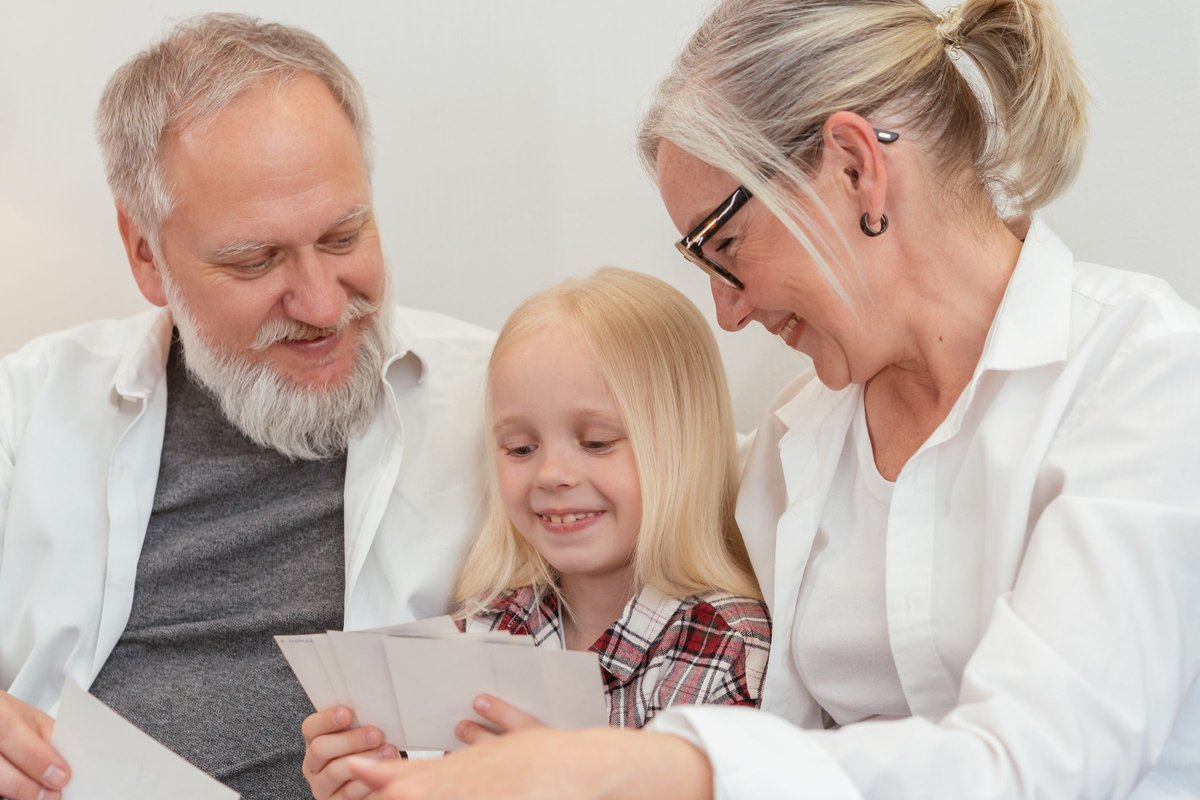 Grandparents and a young girl smiling while looking through printed photos together