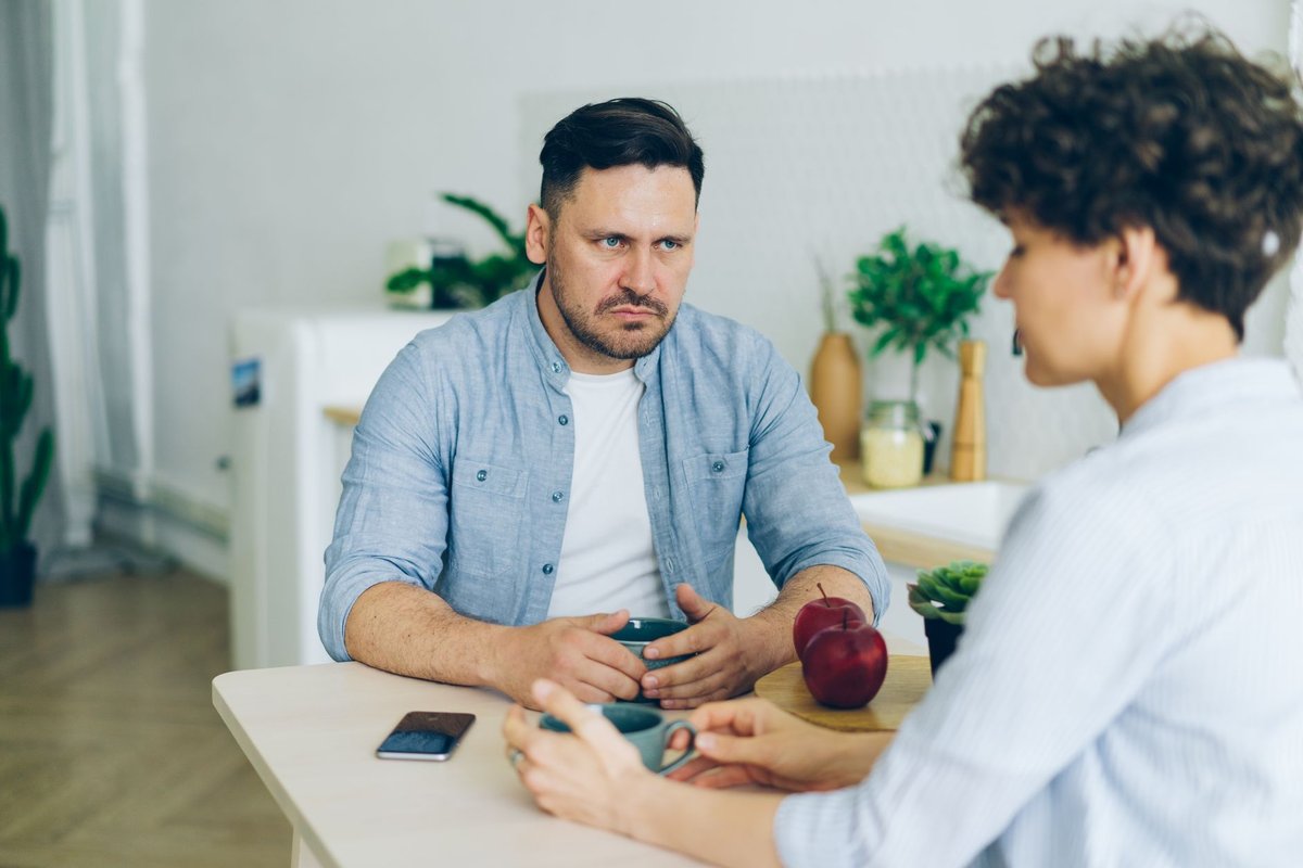 Man and woman sitting at a kitchen table having a serious conversation over coffee