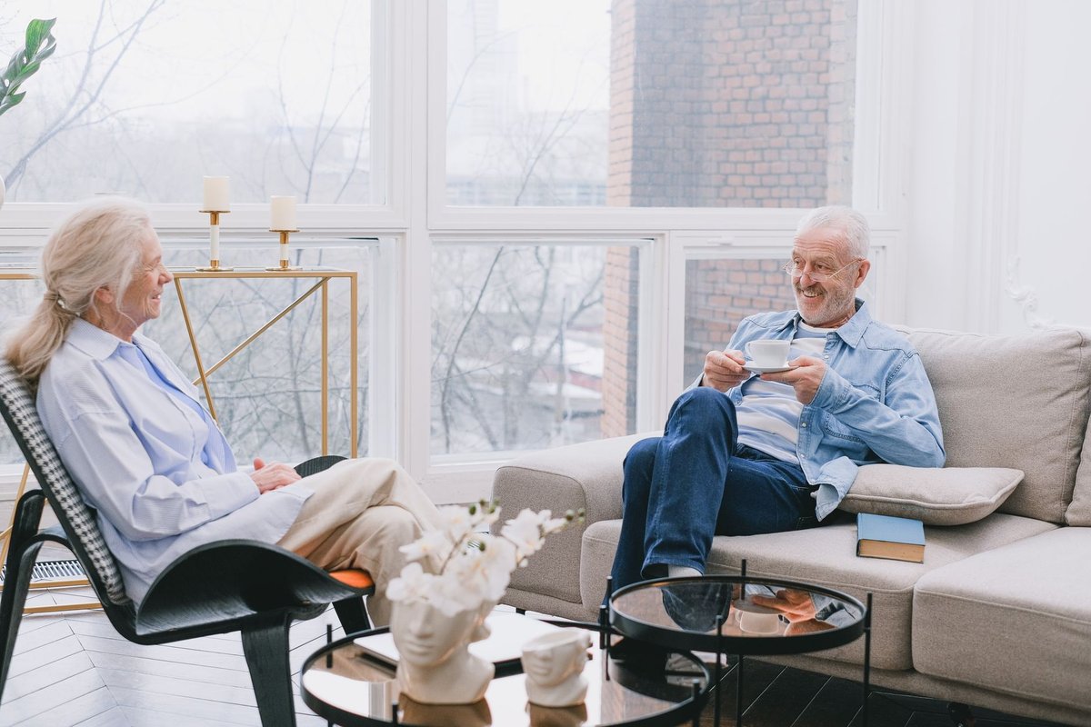 Elderly couple chatting over tea in a bright living room