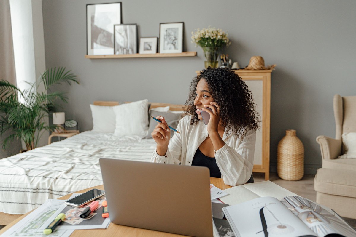 Woman on a phone call at her desk with a laptop and papers