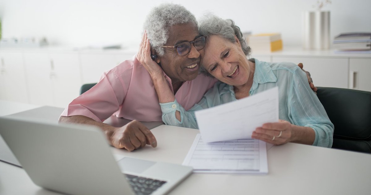 Smiling senior couple looking over paperwork together at a table at home