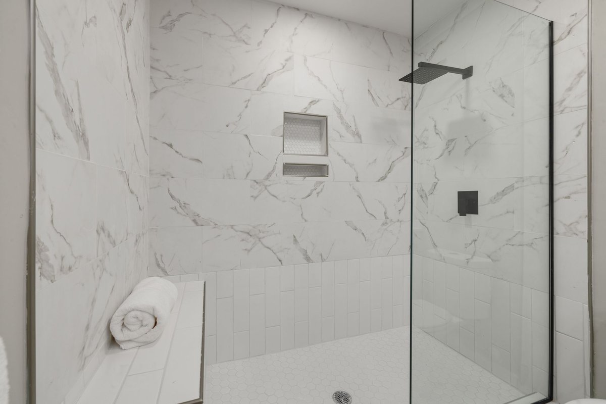 Tiled walk-in shower with a built-in bench and a glass panel
