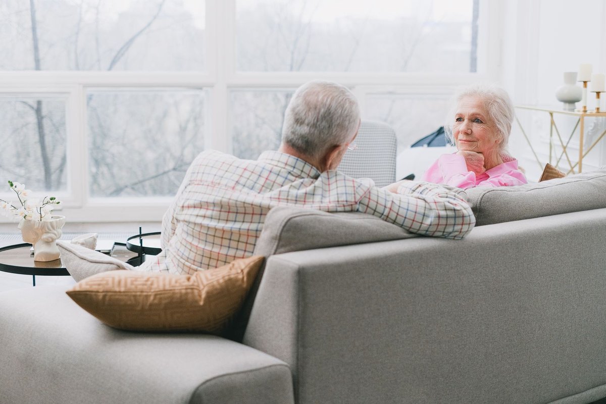 Senior man and woman talking quietly on a sofa in a bright living room