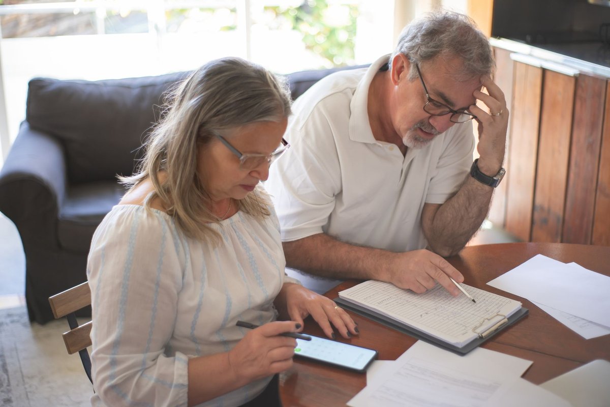 Older couple at a wooden table going through household bills and paperwork together