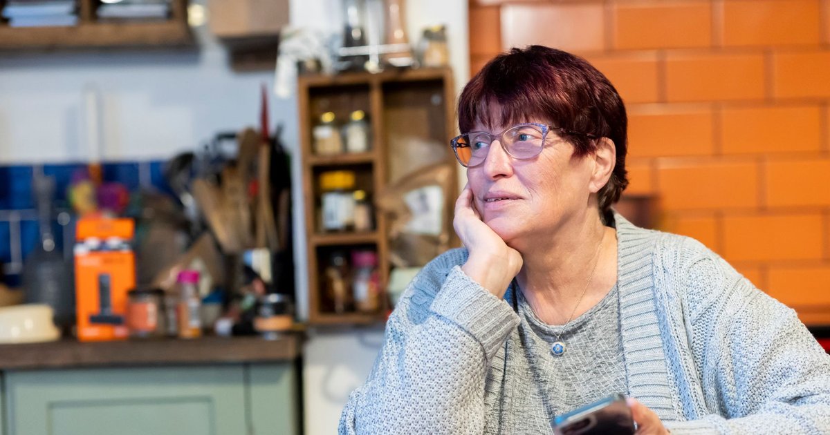 Senior woman at her kitchen table with a phone and notepad thinking about monthly bills