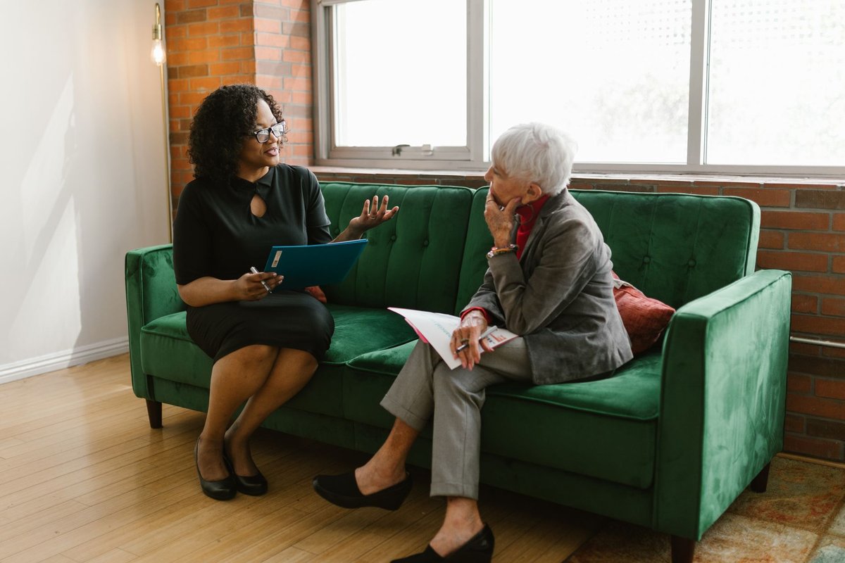 Care coordinator going over a plan with an older woman seated on a sofa