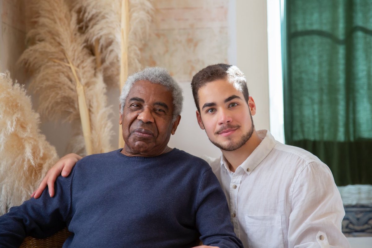 Smiling older man sitting beside a young caregiver at home