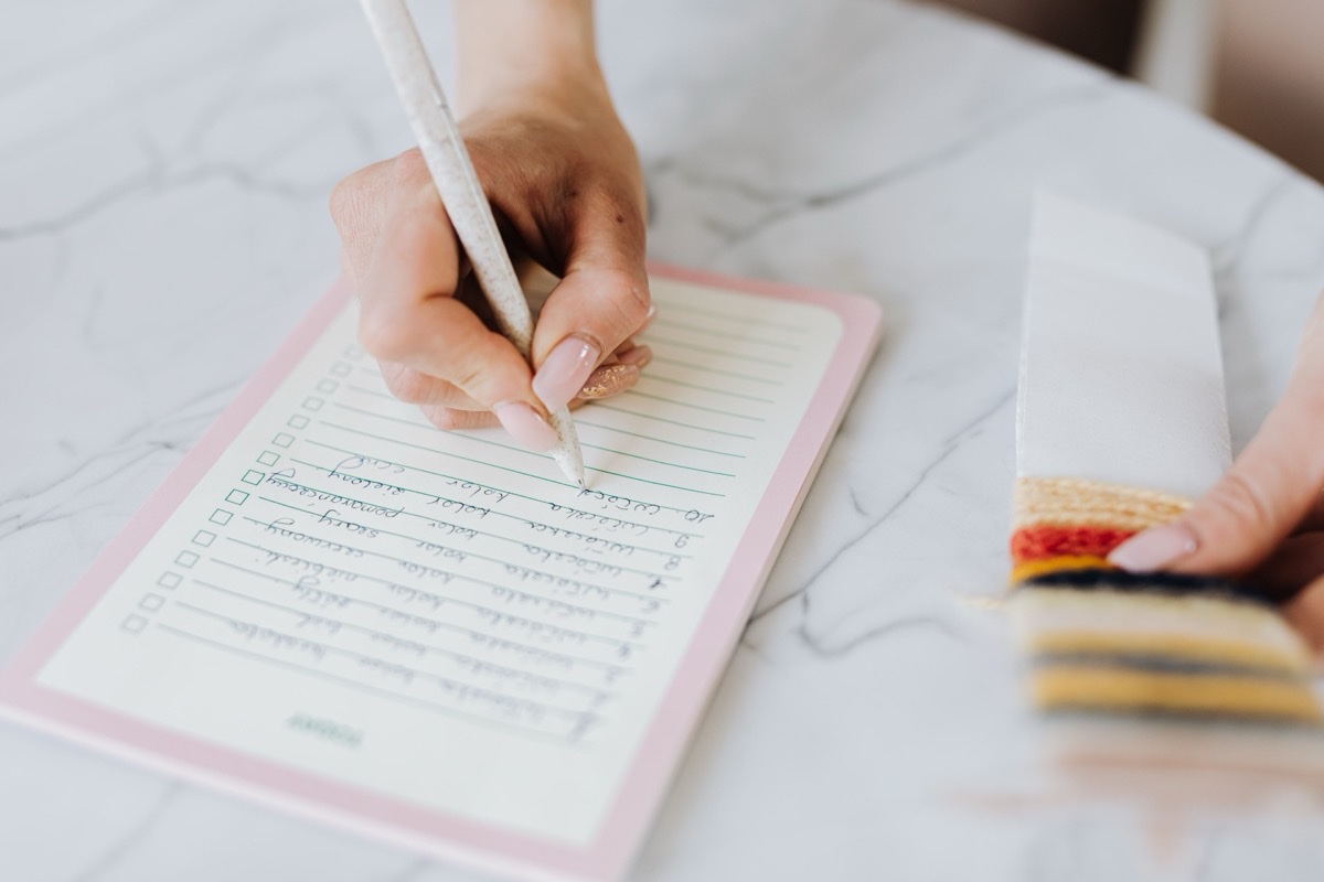 Hand writing a checklist with empty tick boxes in a notebook on a table