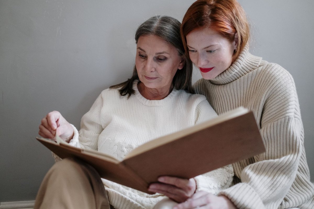 Adult daughter and her mother looking through a photo album together