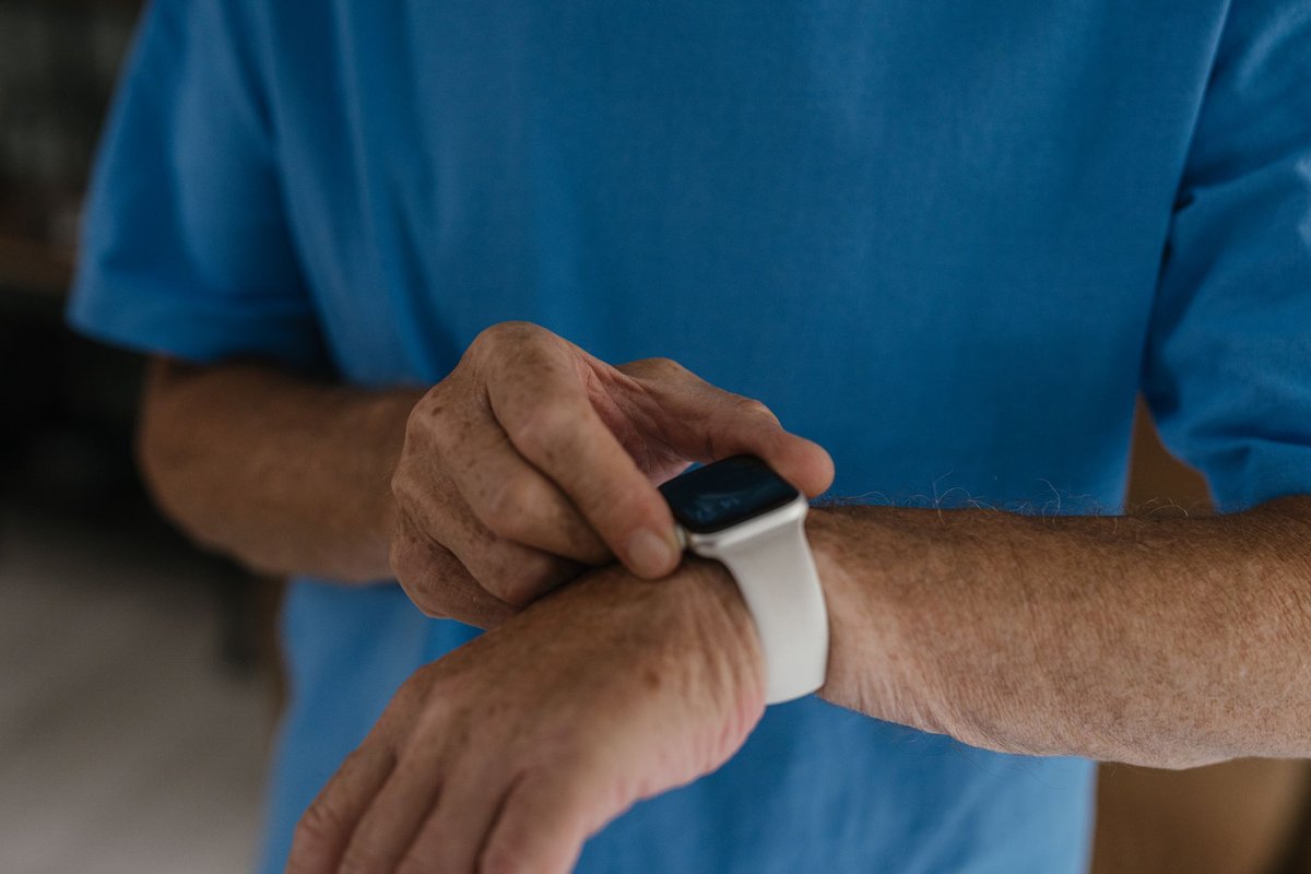 Close-up of an older man's hands adjusting a wristband on his wrist