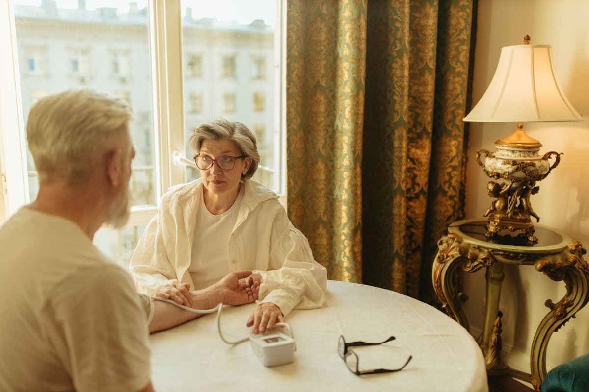Older woman and man at a round table with a home blood pressure cuff on his arm