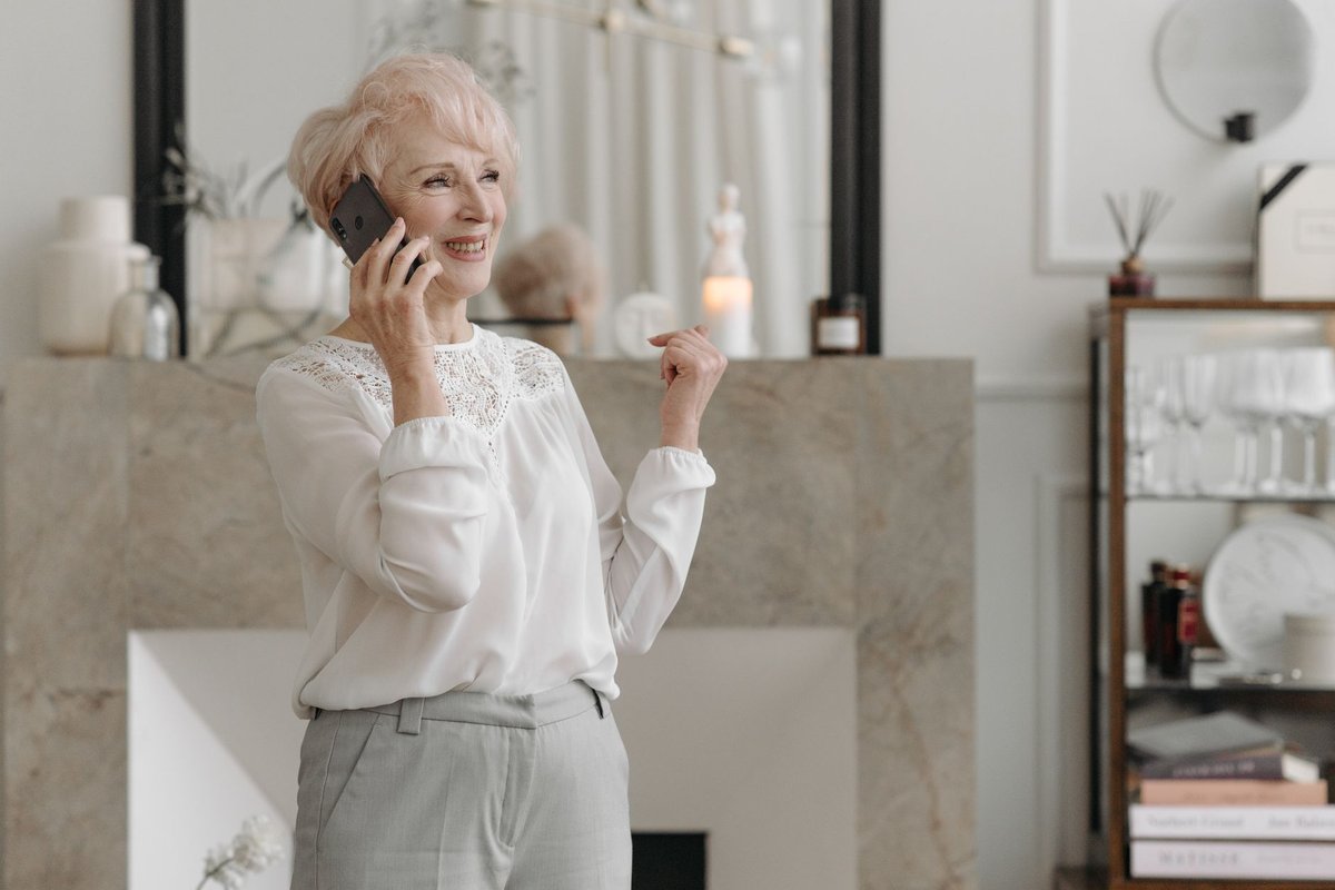 Smiling older woman talking on her phone in a bright living room