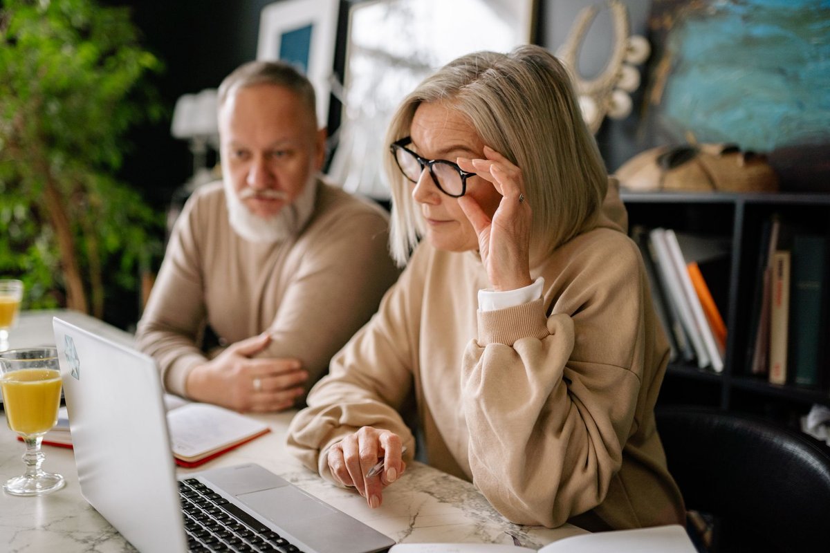 Older woman and man looking at a laptop screen together at a table