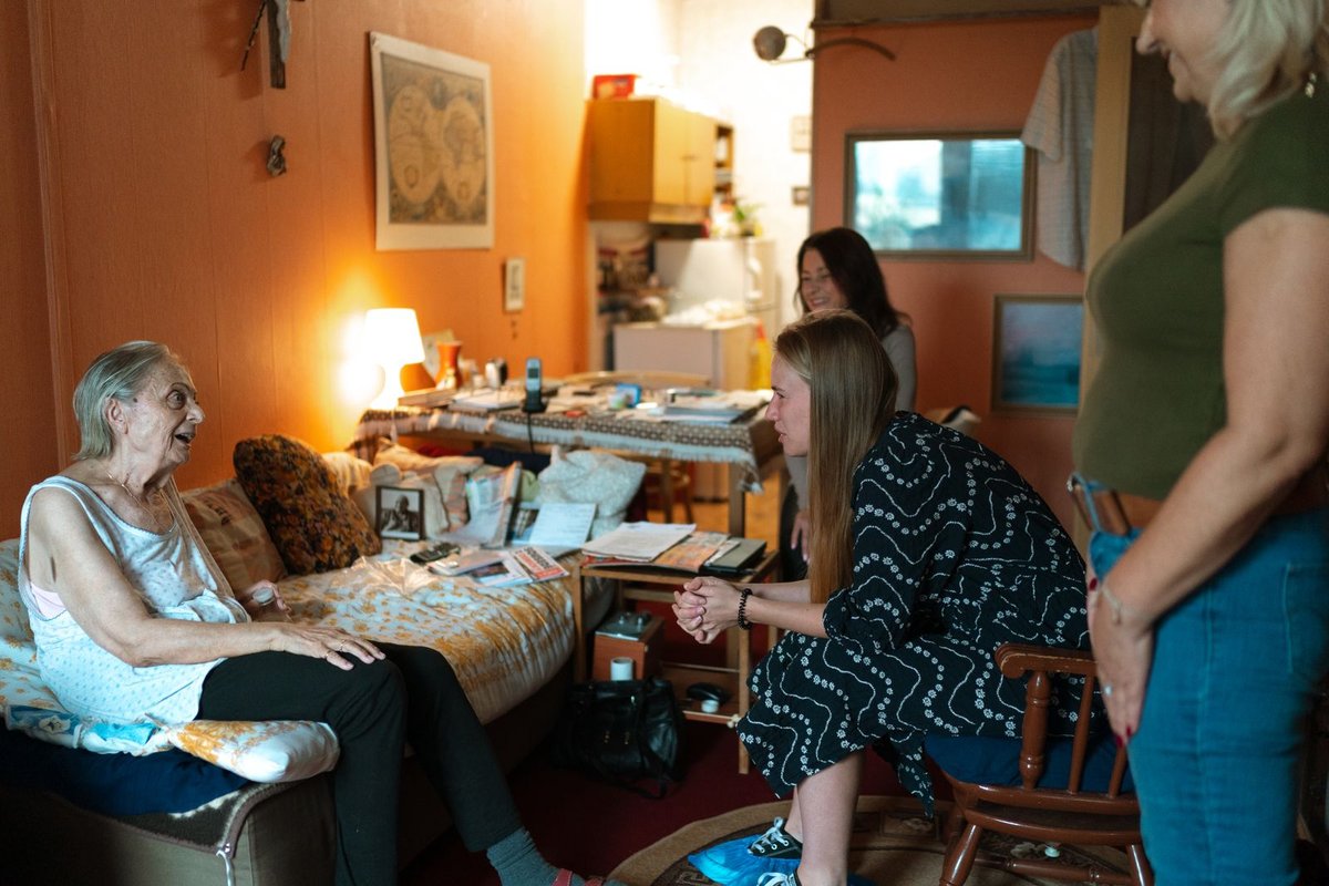 Older woman sitting on her sofa at home talking with visitors in her living room