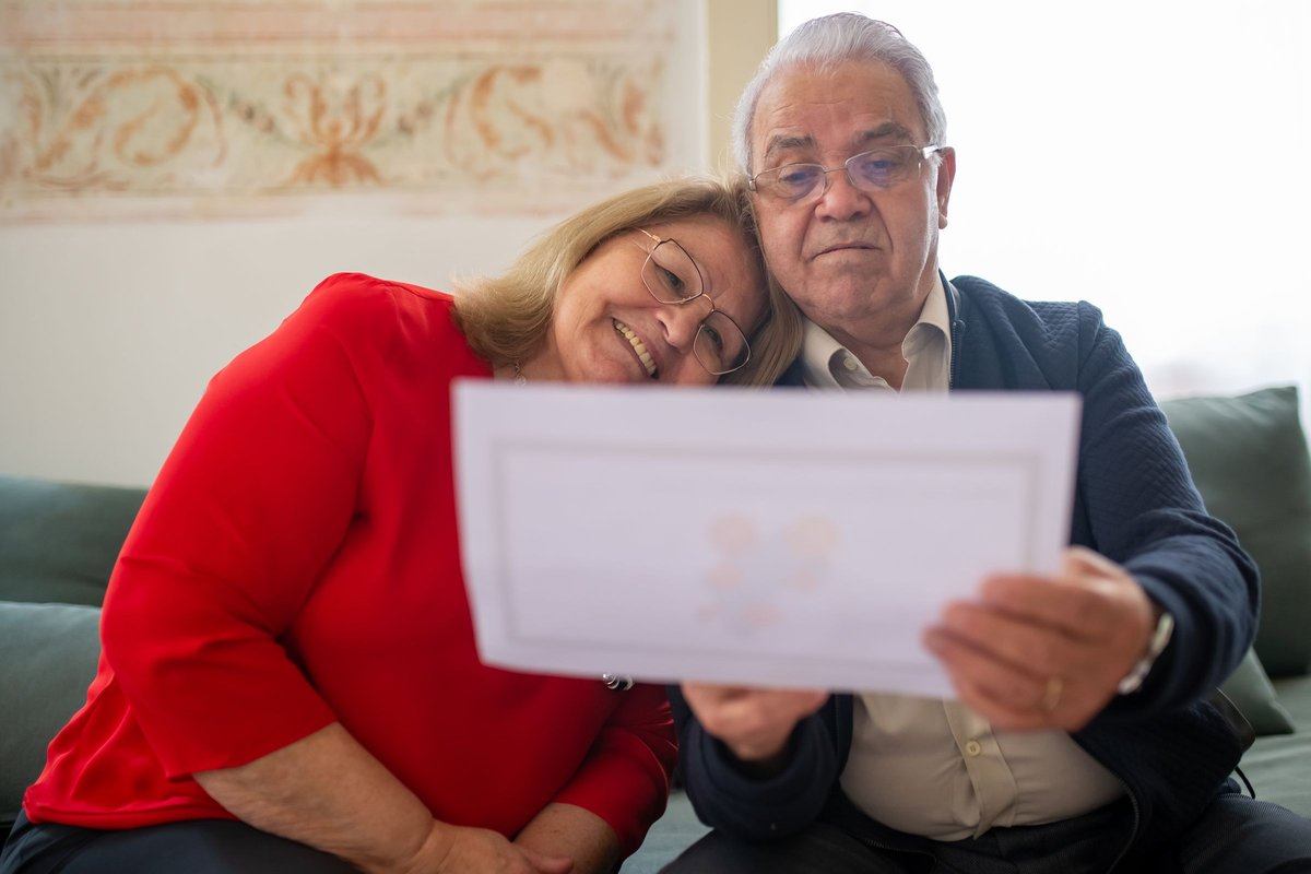 Older couple sitting close on a sofa reading a document together