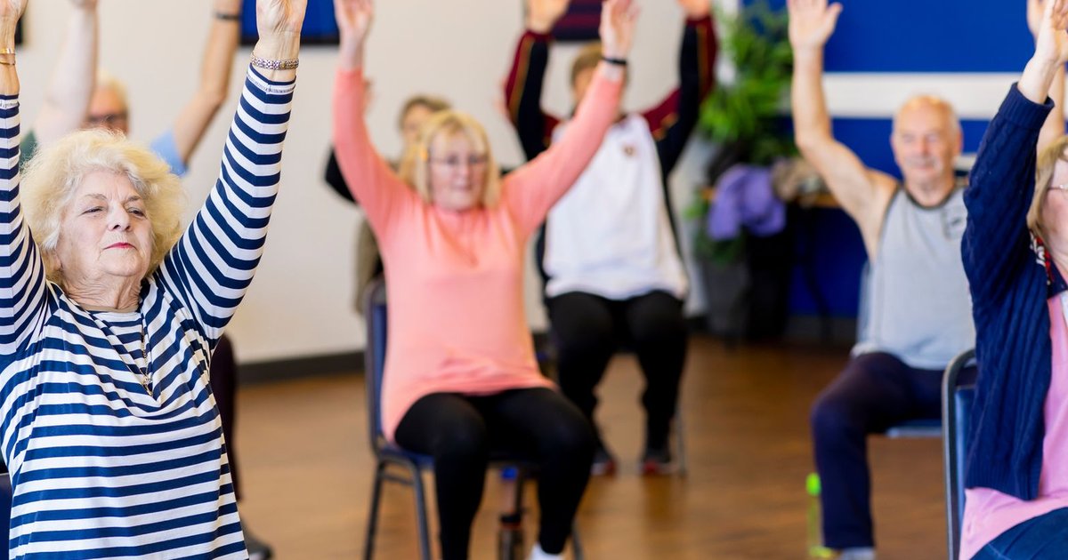 Older adults raising their arms during a chair exercise class at a community center