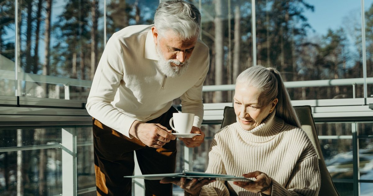 Older couple looking through a folder together in a sunny room with a cup of coffee