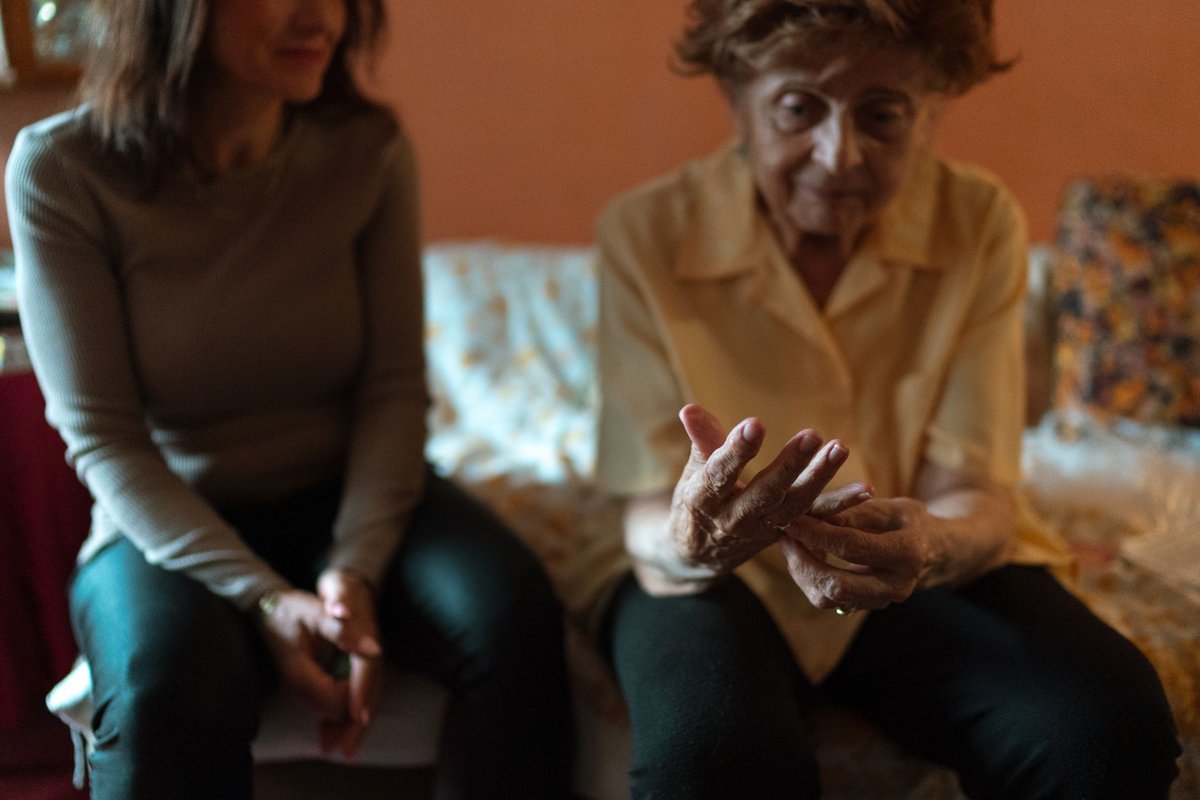 Older woman gestures with her hands while a younger woman sits beside her