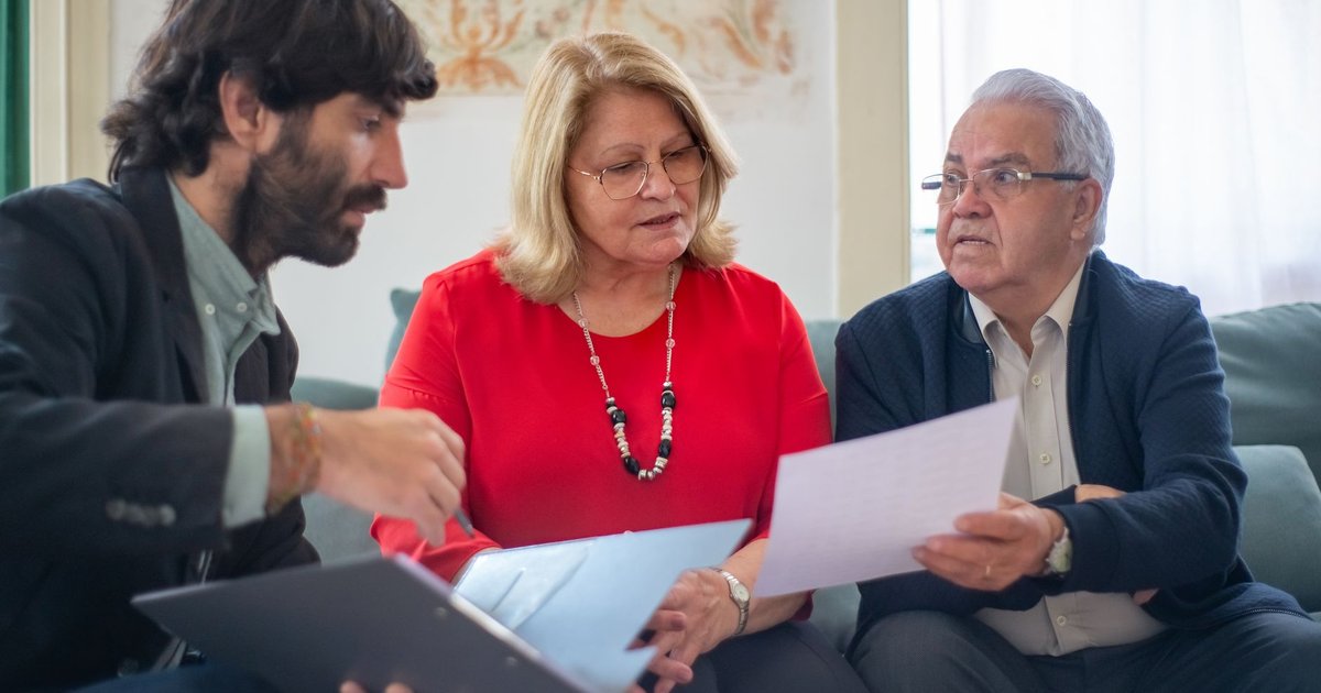 Older couple and an adviser looking over documents together on a sofa