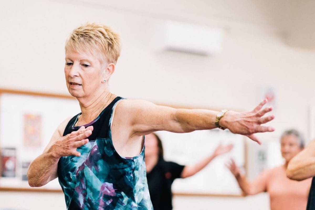 Older woman with short blond hair taking part in a group fitness class