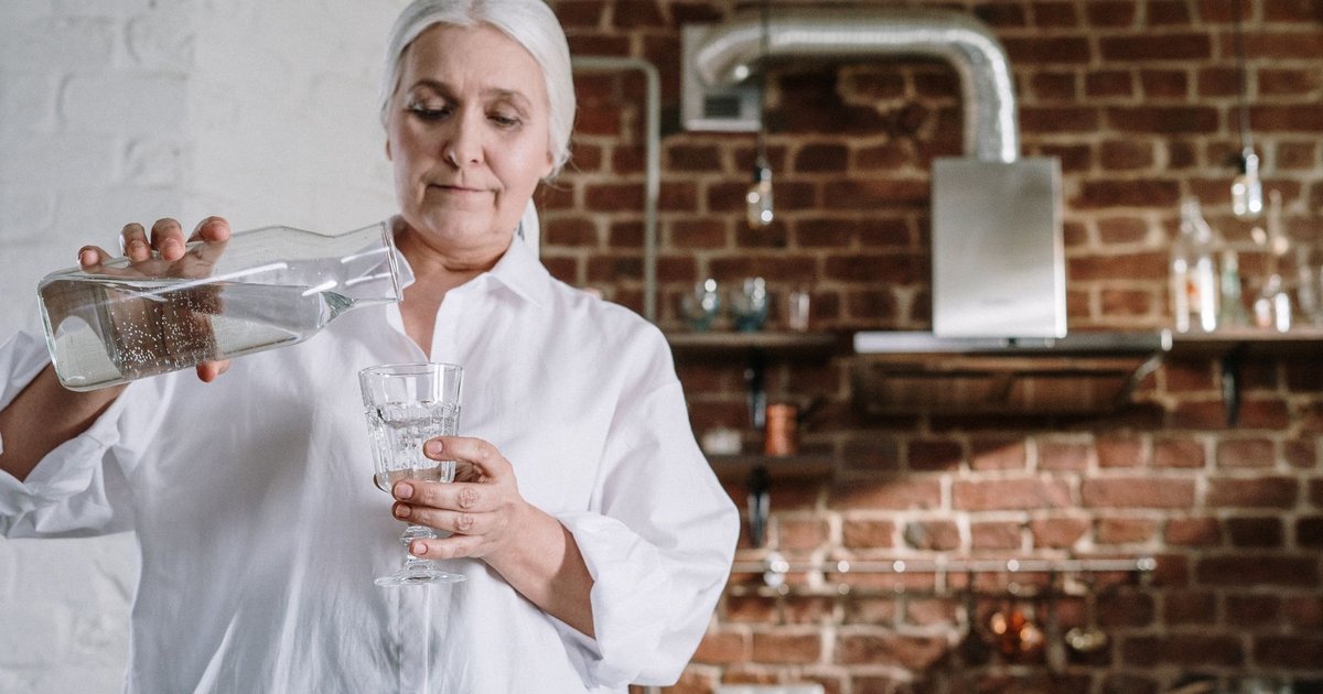 Older woman pouring a glass of water in her kitchen