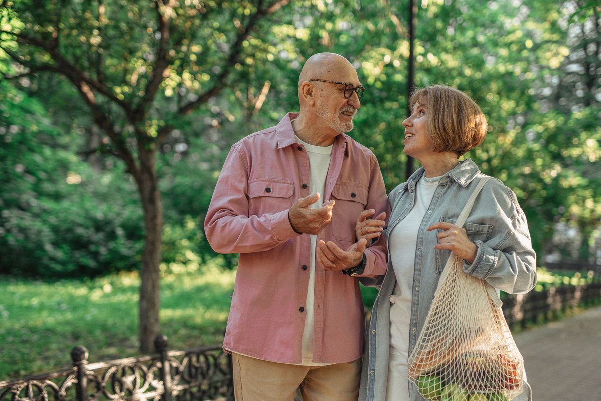 Older couple walking and chatting in a green city park