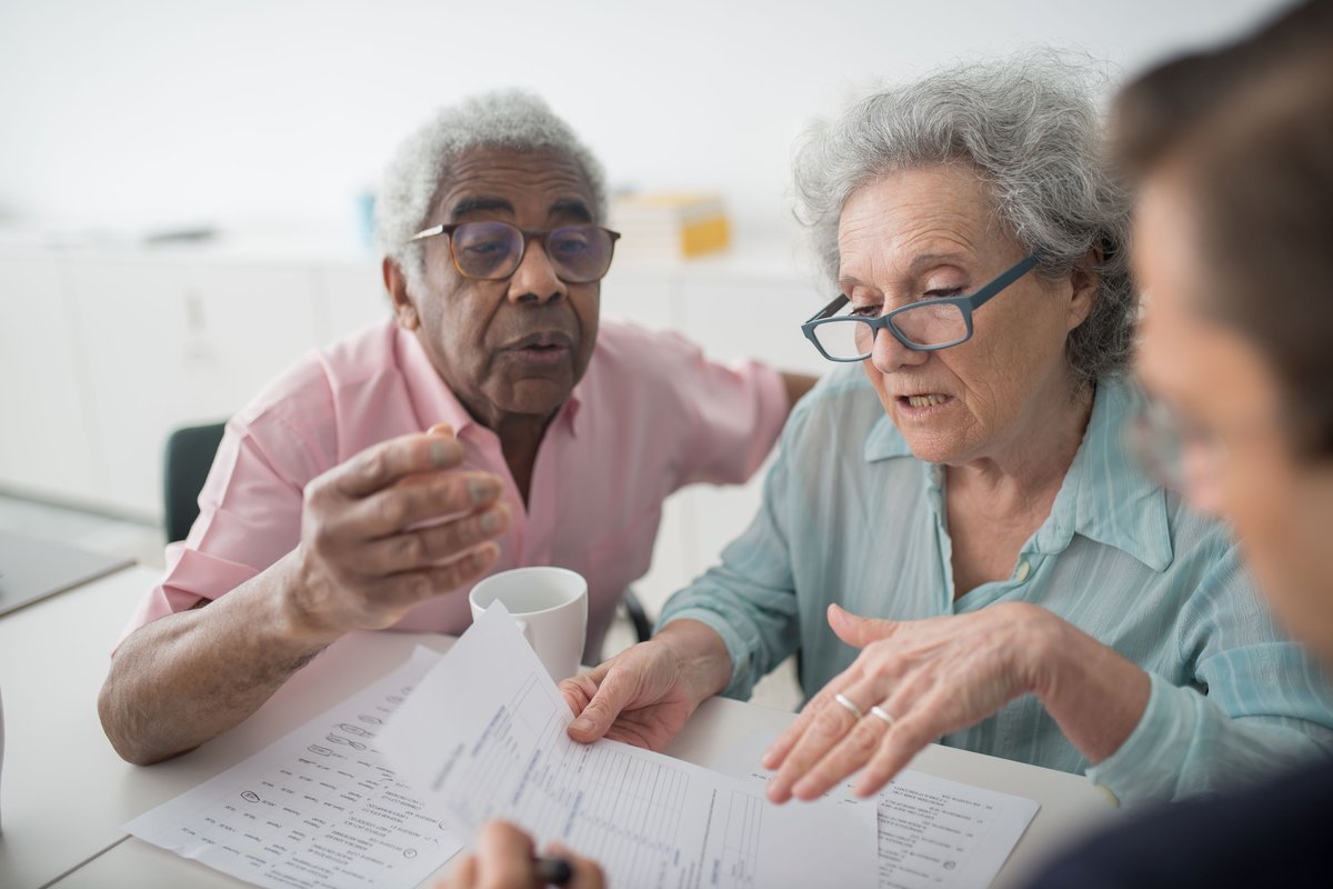 Older couple going over a form with an adviser at a table